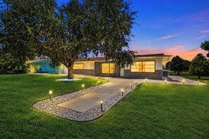 A modern house with a paved driveway, a tree, and a well-maintained lawn.