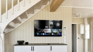 Een moderne keuken met een ingebouwde televisie, witte kastjes en een houten trap.