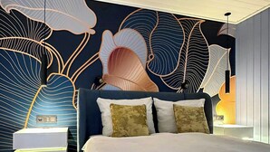 Een moderne slaapkamer met een groot bed, een decoratief behang en een nachtkastje.