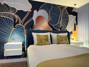 Ein modernes Schlafzimmer mit einem großen Bett, einer Wandmalerei und einem Nachttisch.