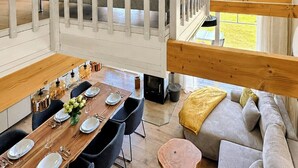Een loft-achtige kamer met een eethoek, een bank en uitzicht op de omgeving.