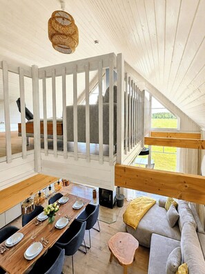 Ein Loft-Zimmer mit Essbereich, einer Couch und Blick ins Freie.