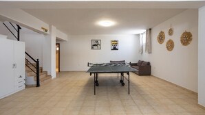 Une pièce spacieuse équipée d’une table de ping-pong, d’un canapé et de décorations murales.
