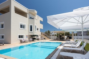 A hotel with a swimming pool, lounge chairs, and umbrellas. - Villa Starlight - Five Bedroom Villa, Sleeps 11 (Lardos)