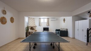 Une pièce spacieuse équipée d’une table de ping-pong, d’une cheminée, d’un canapé et d’une armoire.