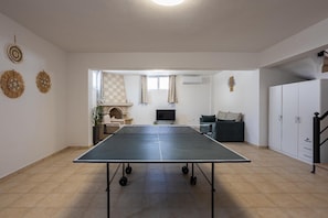 A spacious room with a ping pong table, a fireplace, a sofa, and a wardrobe. - Villa Starlight - Five Bedroom Villa, Sleeps 11 (Lardos)