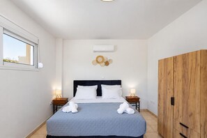 Ein Schlafzimmer mit einem Bett, Nachttischen, einer Klimaanlage, einem Holzschrank und einem Fenster.