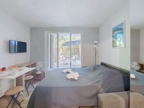 Ein Hotelzimmer mit einem Bett, einem Schreibtisch, einem Sessel, einem Fernseher und Blick ins Freie.
