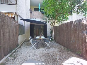 Eine Terrasse im Freien mit Tisch und Stühlen, umgeben von einem Holzzaun und Kies.