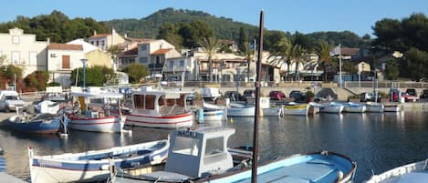 A marina with various boats docked, a hotel, and buildings in the background.