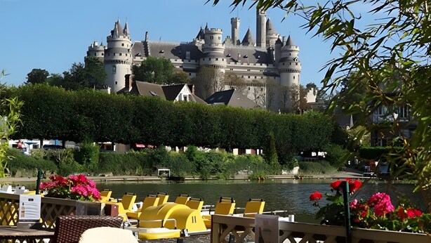 Una estructura que parece un castillo, con un foso y barcas amarillas al frente.