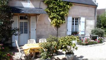 Une maison dotée d’un patio couvert, d’un espace salon extérieur et de plantes en pot.