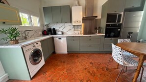 Una cocina compacta con lavadora, lavavajillas y un comedor con mesa y sillas.