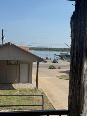 A view of a building with a garage, a driveway, and a body of water in the background. - Rocker B is only a 10 minute drive away from this cute lake front cabin (Graford)