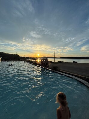 A swimming pool with a sunset view, a road, and a distant hill. - Rocker B is only a 10 minute drive away from this cute lake front cabin (Graford)