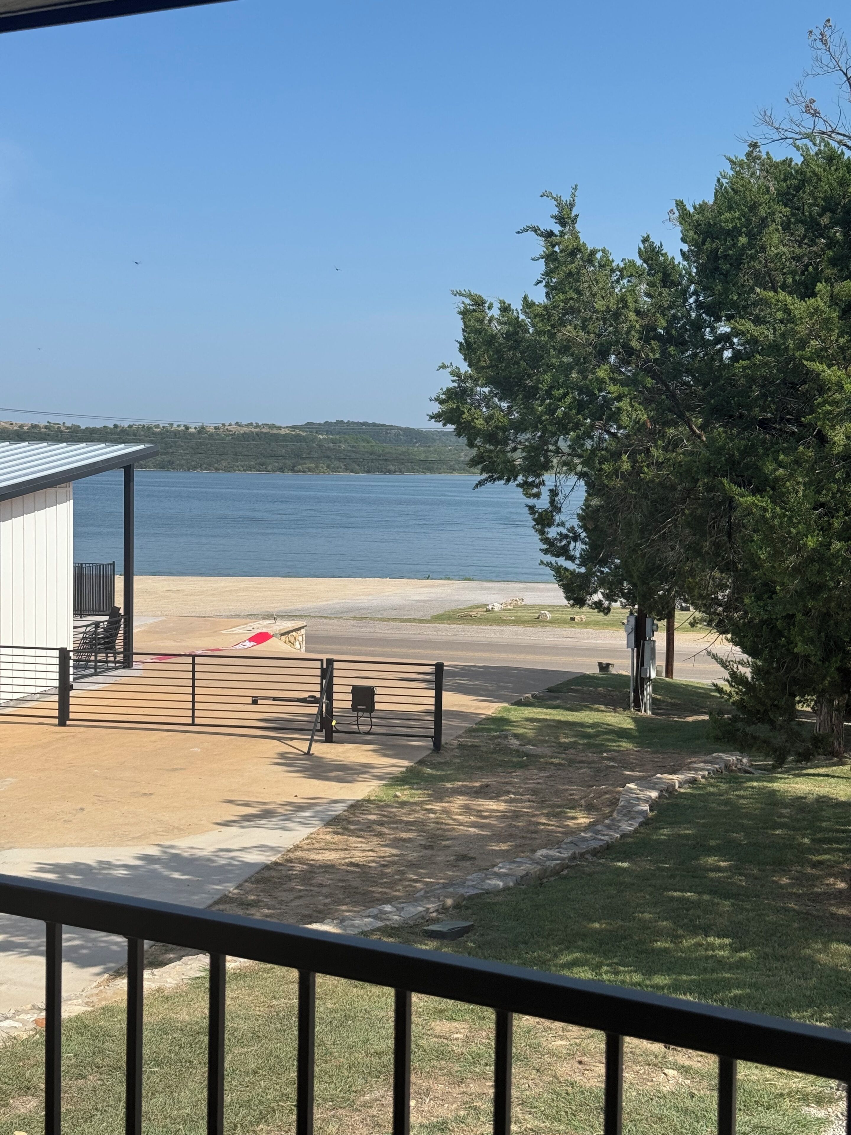 A beach view with a building, a fenced area, and a tree.