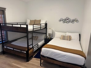 A bunk bed room with a single bed, a nightstand with a lamp, and a wall decoration of bicycles. - Rocker B is only a 10 minute drive away from this cute lake front cabin (Graford)