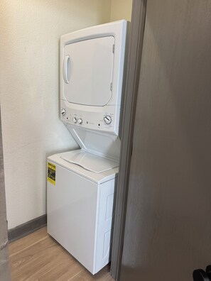 Ein kompaktes, weißes, wandmontiertes Wasch- und Trockner-Kombigerät mit Bedienfeld und einem gelben Energielabel.