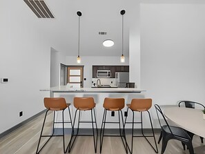 A modern kitchen with a central island, overhead pendant lighting, and a dining area with four chairs. - Rocker B is only a 10 minute drive away from this cute lake front cabin (Graford)