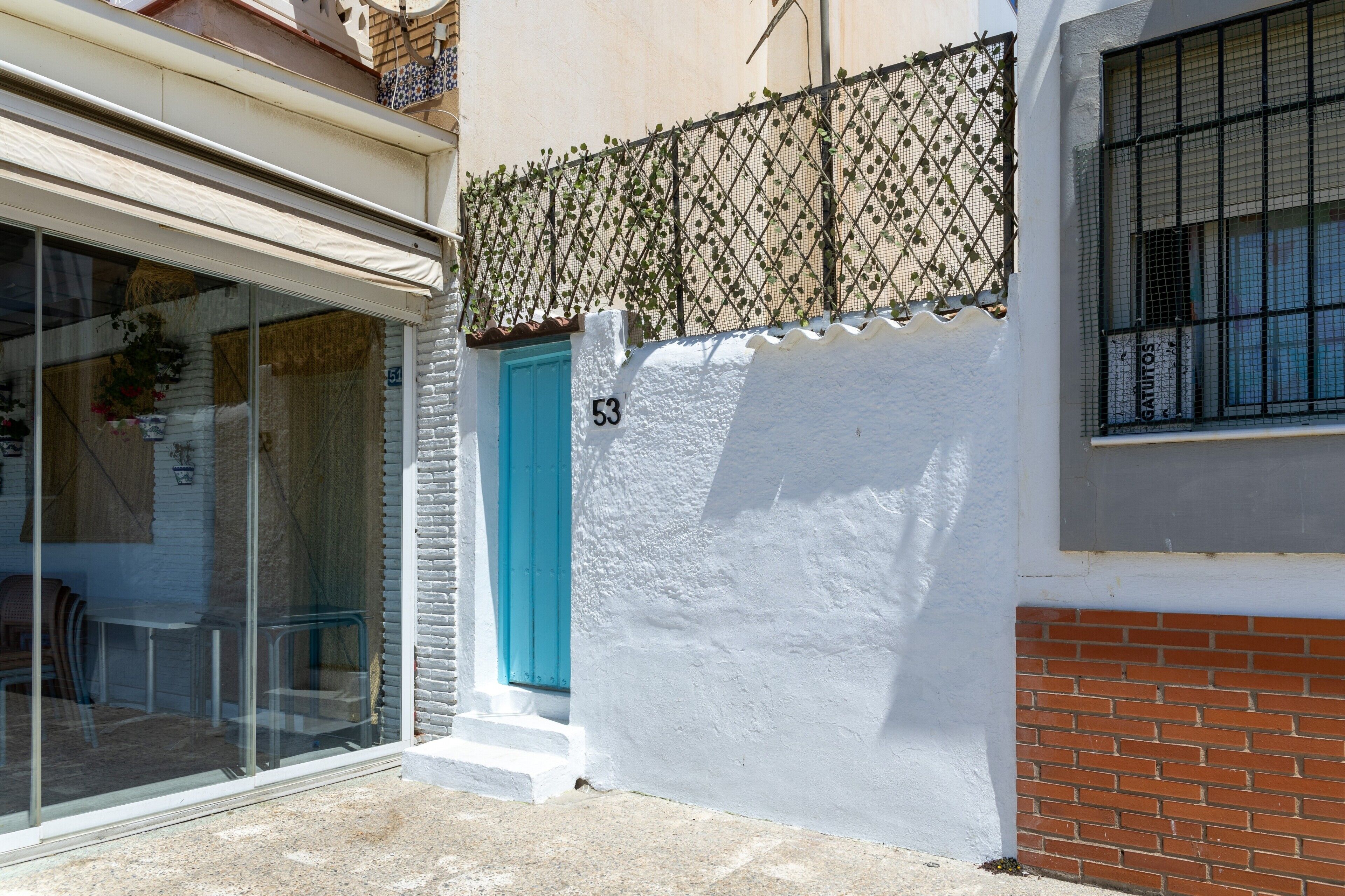 A building with a white facade, a blue door, and a number '53' on the wall.
