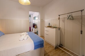 Ein Schlafzimmer mit einem Bett, einem Kleiderschrank, einem Schreibtisch und einem Spiegel.