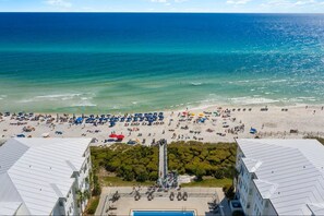 A beach with umbrellas and people, a pool, and buildings with a modern design. - 🌴 Red Rooster | 30A Luxury Home | 3 Kings, Pool & Beach Access 🏖️ (Seacrest Beach)