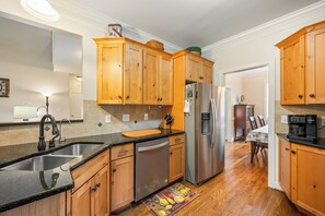 A modern kitchen with wooden cabinets, stainless steel appliances, and a black countertop. - Boonsboro Escape (Lynchburg)