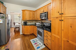 A kitchen with wooden cabinets, a stainless steel refrigerator, a microwave, a stove, and a coffee maker. - Boonsboro Escape (Lynchburg)