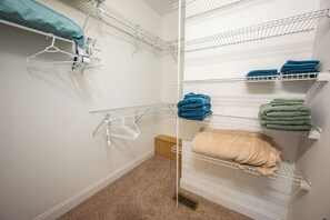 A walk-in closet with multiple shelves for hanging clothes, a metal drying rack, and a wooden cabinet. - Boonsboro Escape (Lynchburg)