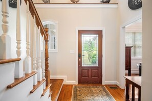 A wooden staircase with white balusters leading to a door with a glass panel. - Boonsboro Escape (Lynchburg)