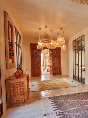 A hallway with a patterned rug, wooden cabinet, hanging lights, and a view into another room. - Palais Baraya (Essaouira)