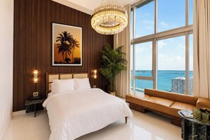 A hotel room with a large bed, a view of the ocean, a sofa, and a chandelier. - Luxury suite with city and bay views in Miami (Miami)