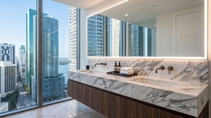 A modern bathroom with a large mirror, dual sinks, and a view of a cityscape through floor-to-ceiling windows. - Luxury suite with city and bay views in Miami (Miami)