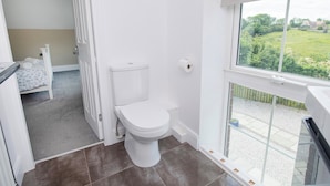 Ein Badezimmer mit Toilette, Dusche und einem Fenster mit Gartenblick.