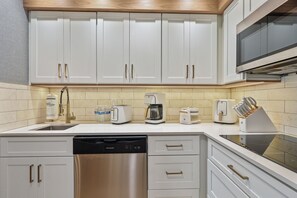 Een moderne keuken met witte kasten, roestvrijstalen apparatuur en een betegelde achterwand.