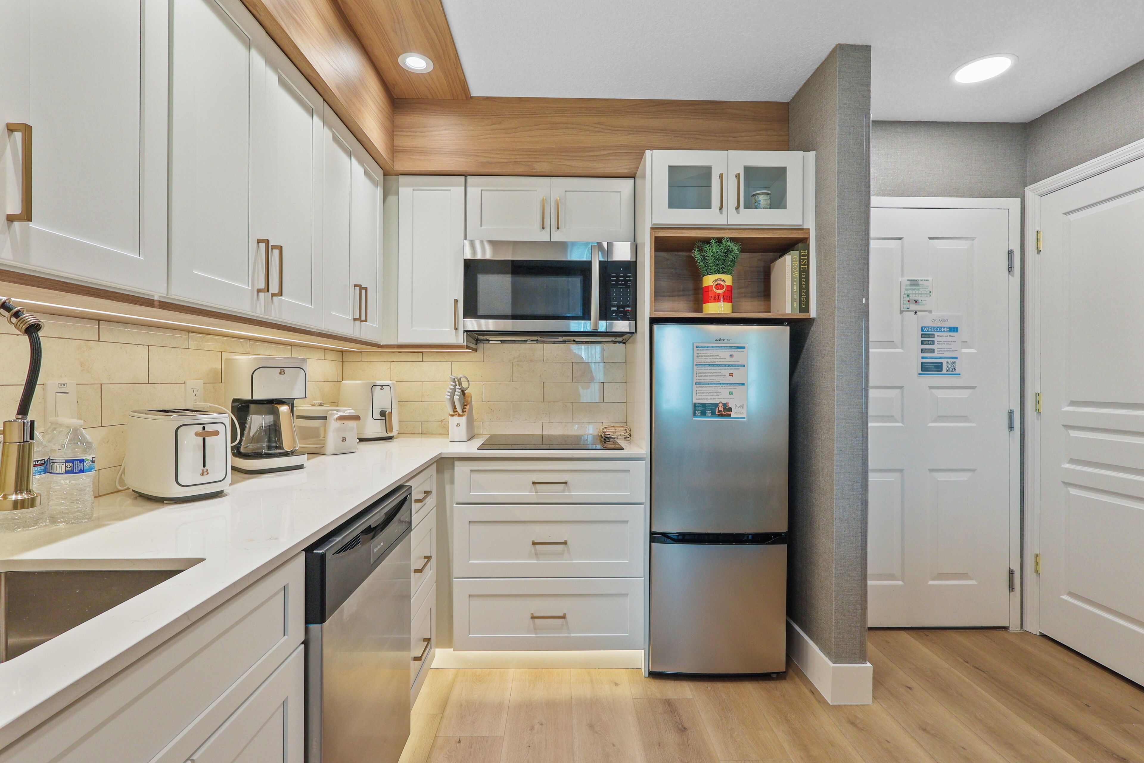 Una cocina moderna con gabinetes blancos, electrodomésticos de acero inoxidable y un microondas integrado.