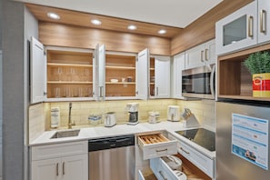 A modern kitchen with white cabinetry, a built-in oven, and a coffee maker. - 1BR apartment with 2 queens near Disney (Orlando)