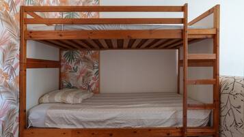 Een stapelbed met een houten frame, een matras met gestreept beddengoed en een kussen.