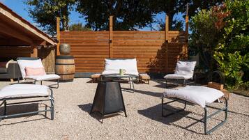 An outdoor seating area with metal chairs and a table, surrounded by a wooden fence and trees.
