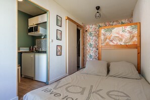 A compact bedroom with a bunk bed, a kitchenette, and a bathroom.