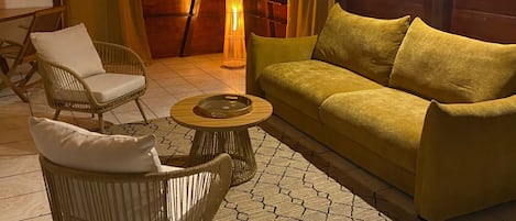 A cozy room with a wooden ceiling, a sofa, a chair, a small table, and a floor lamp.