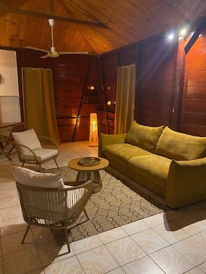 A cozy room with a wooden ceiling, a sofa, a chair, a small table, and a floor lamp. - Creole House on the Beach - Double Bed - Free Parking (Deshaies)