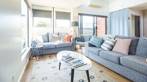 Een moderne woonkamer met een grijze bank, een salontafel en een kamerbreed tapijt met een patroon.