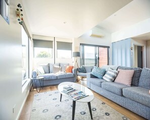 A modern living room with a grey sofa, a coffee table, and a patterned rug. - Villa Callista - Modern Coastal Escape (Port Sorell)