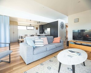 Ein modernes Wohnzimmer mit einem grauen Sofa, einem Couchtisch und einem Fernseher.