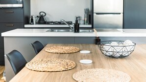 Een moderne keuken met een houten eettafel, geweven placematen en een decoratieve mand.