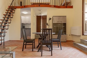 Un comedor con mesa y sillas, una cocina al fondo y una escalera de madera.