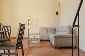 Un salon comprenant un canapé, des fauteuils, une table et un lampadaire.