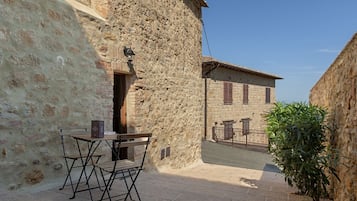 Edifici de pedra amb una petita zona d'seure a l'exterior i una taula de metall.