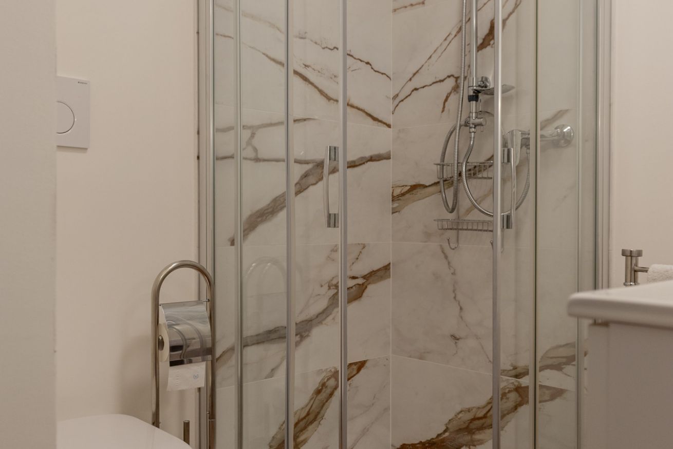 Un baño con cabina de ducha de vidrio, perchero y retrete.